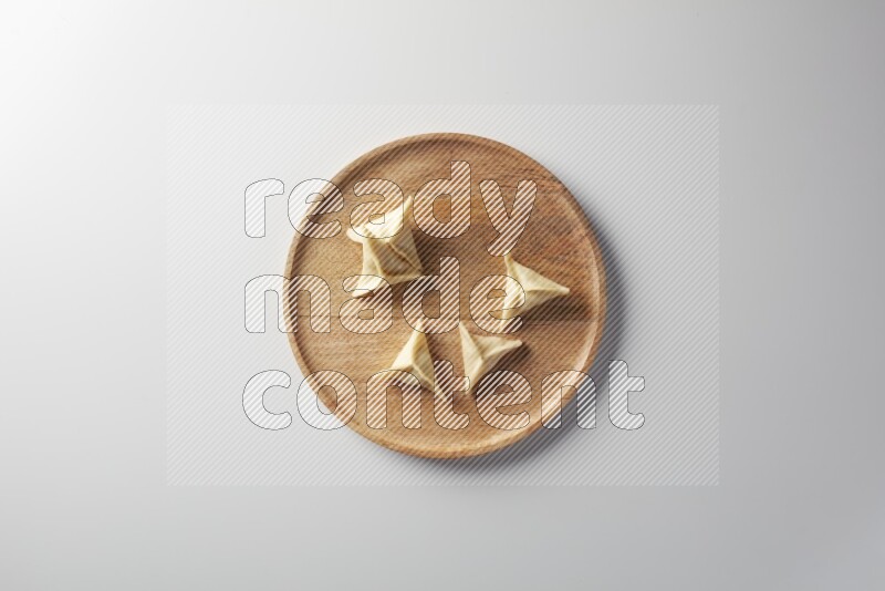 Five Sambosas on a wooden round plate on a white background