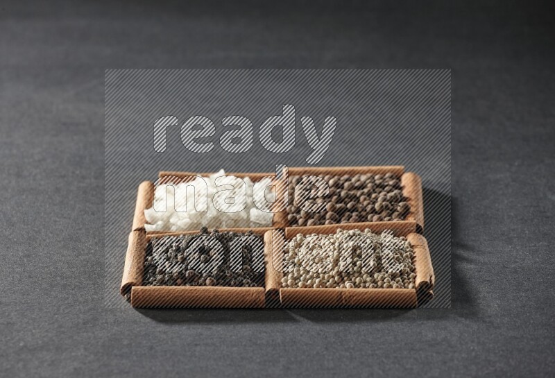 4 squares of cinnamon sticks full of black pepper, white pepper, allspice and white salt on black flooring