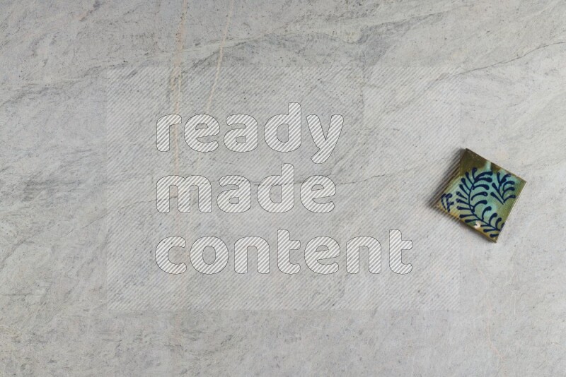 A decorative pottery coaster on grey marble background
