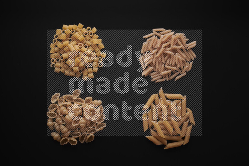 Different pasta types in bunches on black background