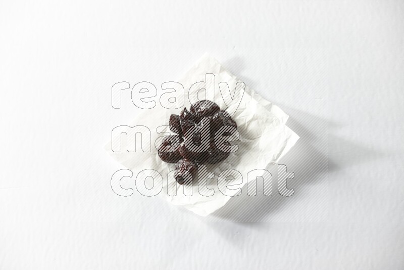 Dried plums on a crumpled piece of paper on a white background in different angles