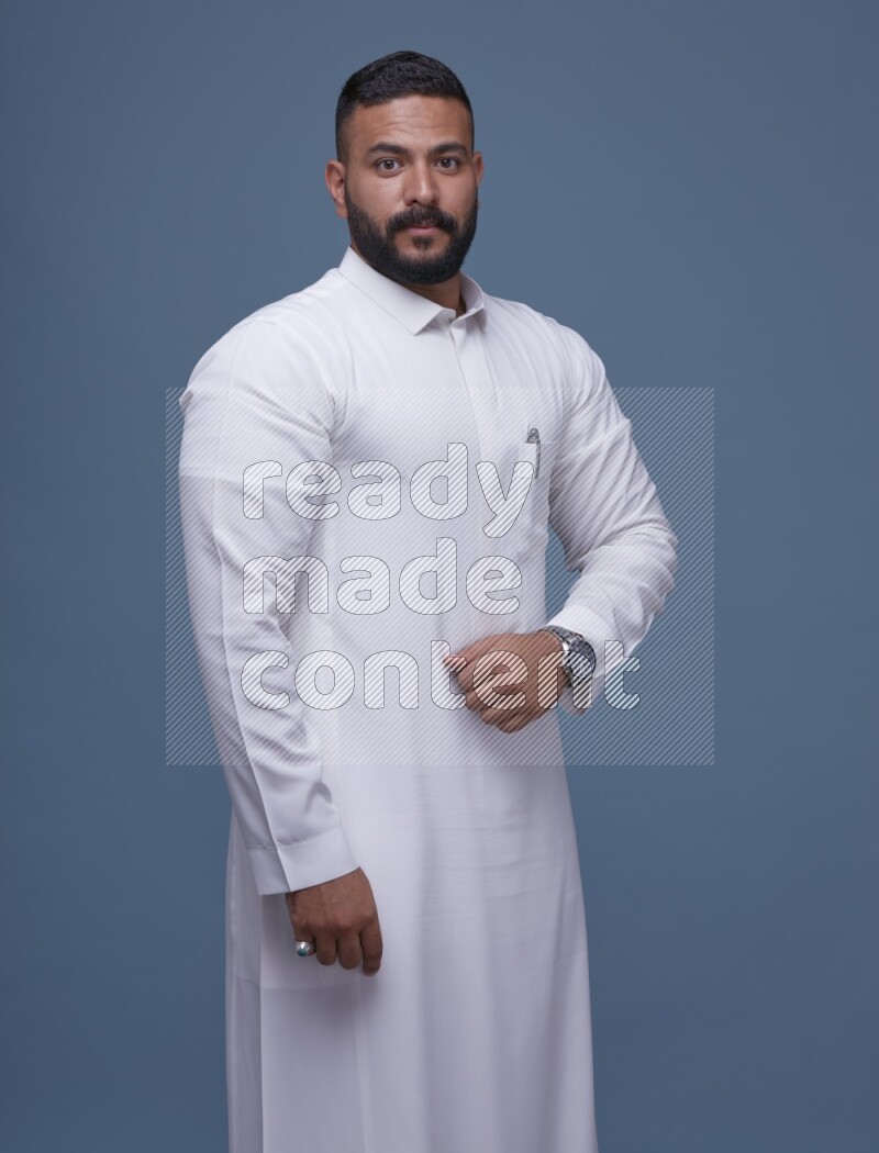 A man Posing in Blue Background wearing a Saudi Thob