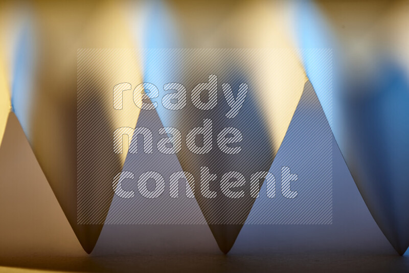 A close-up abstract image showing sharp geometric paper folds in blue gradients and warm tones