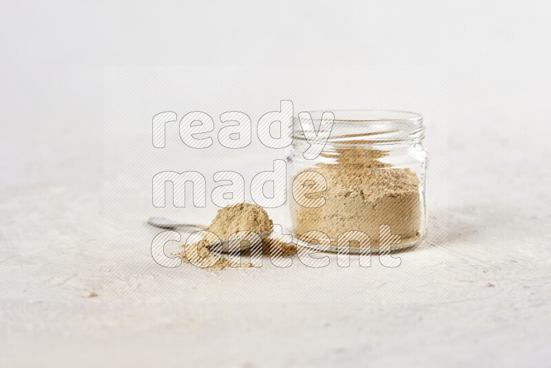 A glass jar full of ground ginger powder on white background