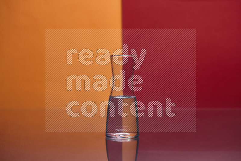 The image features a clear glassware filled with water, set against orange and red background
