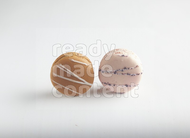 45º Shot of of two assorted Brown Irish Cream, and pink orange blossom macarons on white background