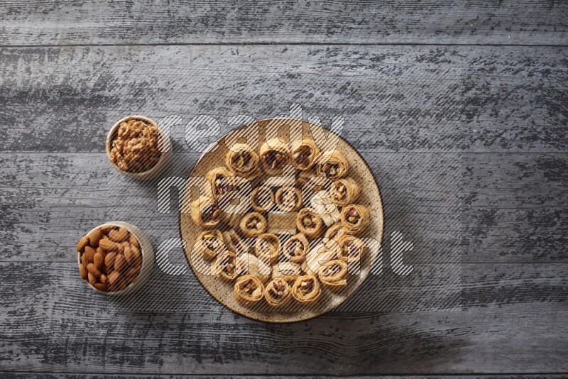 Oriental sweets in a pottery plate with nuts, coffee and honey in a dark setup