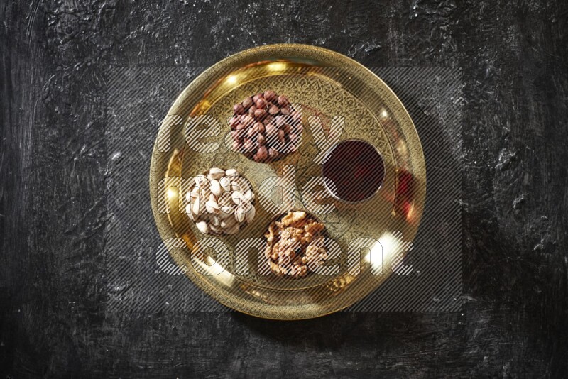 Nuts in metal bowls with Hibiscus on a tray in dark setup