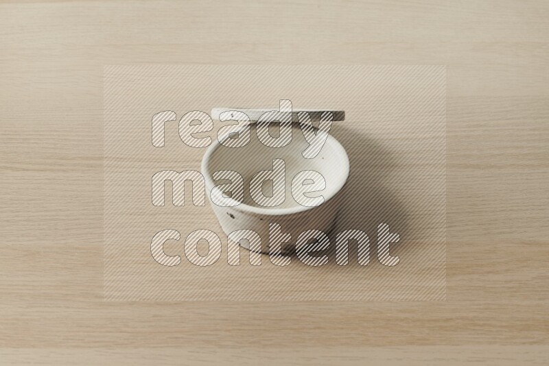 A white pottery bowl on light wooden background
