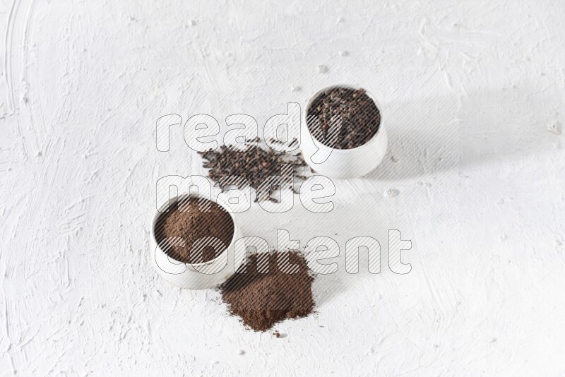 2 Beige ceramic bowls, one full of cloves and the other full of powder on textured white flooring