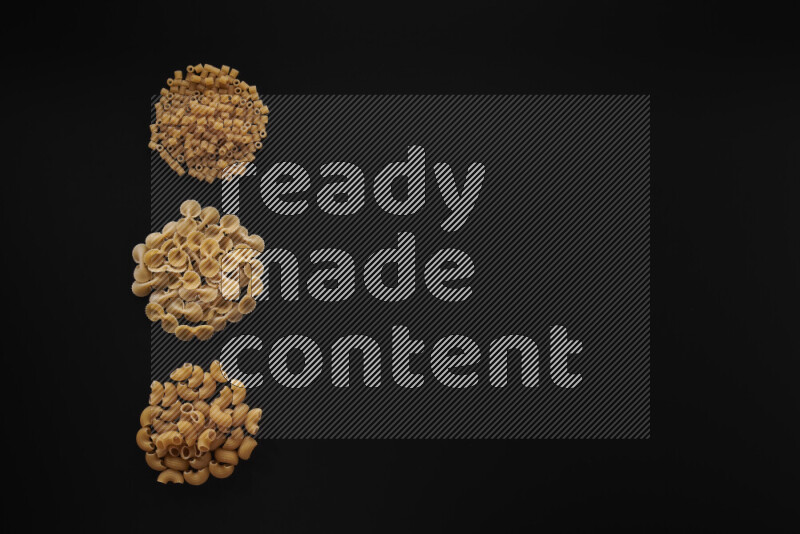 Different pasta types in 3 bunches on black background