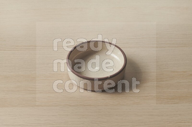 A beige pottery oven bowl on light wooden background