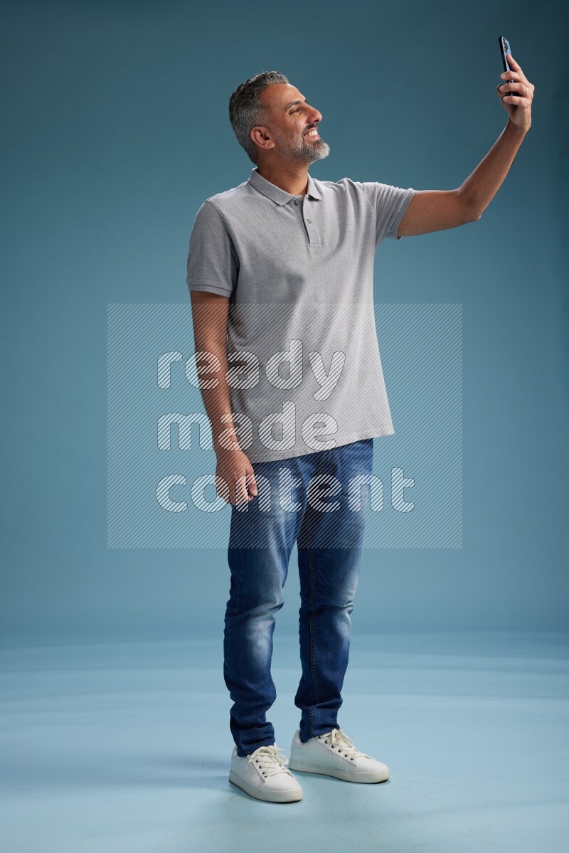 Man Standing taking selfie on blue background