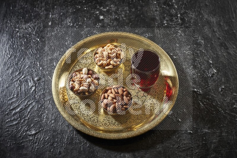 Nuts in metal bowls with Hibiscus on a tray in dark setup