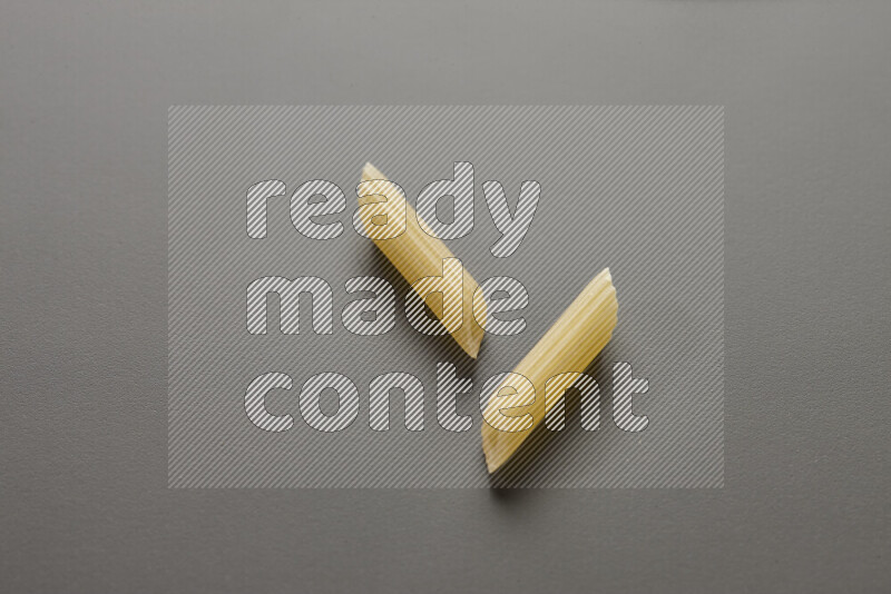 Mini penne pasta on grey background