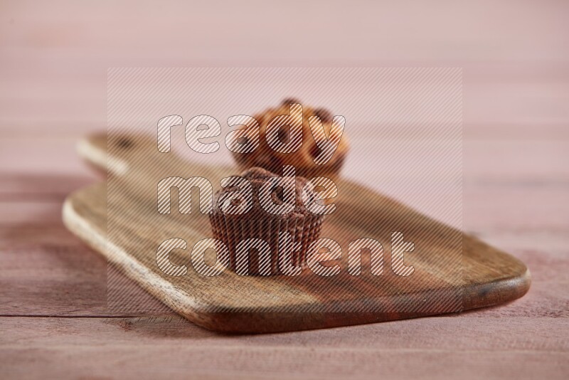 Chocolate mini cupcake topped with chocolate chips on a wooden board