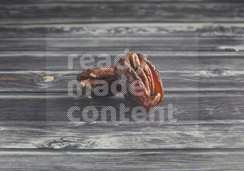 two pecan stuffed madjoul date on a wooden grey background