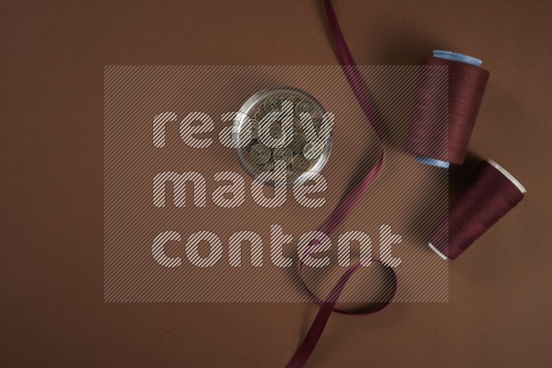 مجموعة من أدوات الخياطة والتفصيل حمراء اللون على خلفية بنية