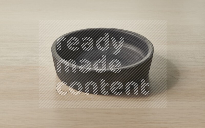 A black pottery bowl on light wooden background