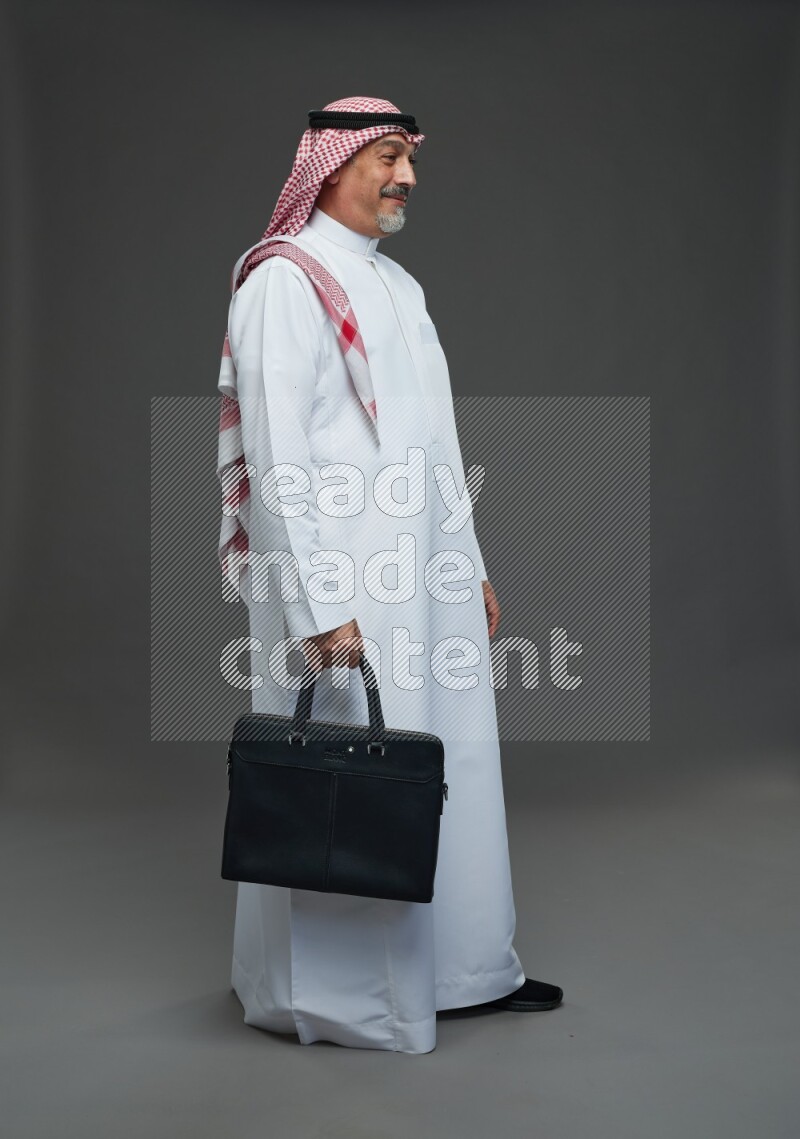 Saudi man with shomag Standing holding bag on gray background