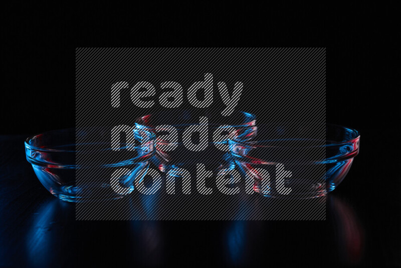 Glassware with rim light in red and blue against black background