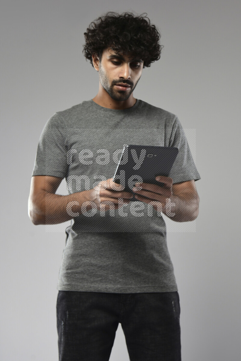 A man wearing casual standing and browsing on a tablet on white background