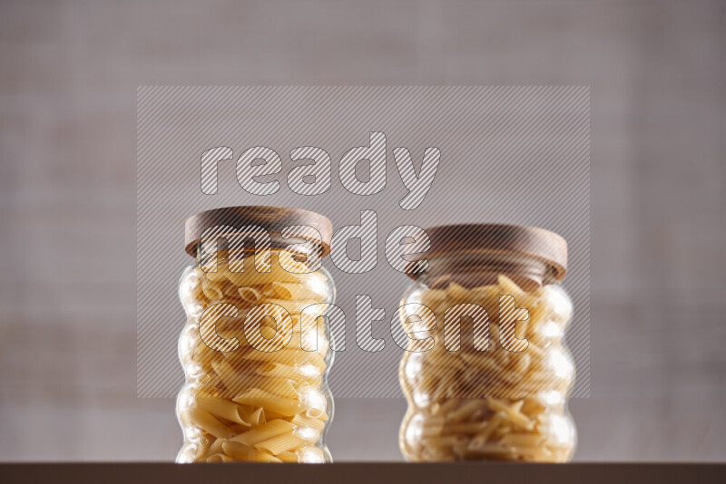 Raw pasta in glass jars on beige background