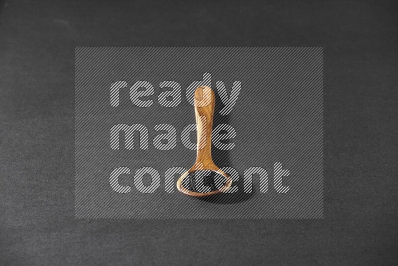 A wooden ladle full of black seeds on a black flooring