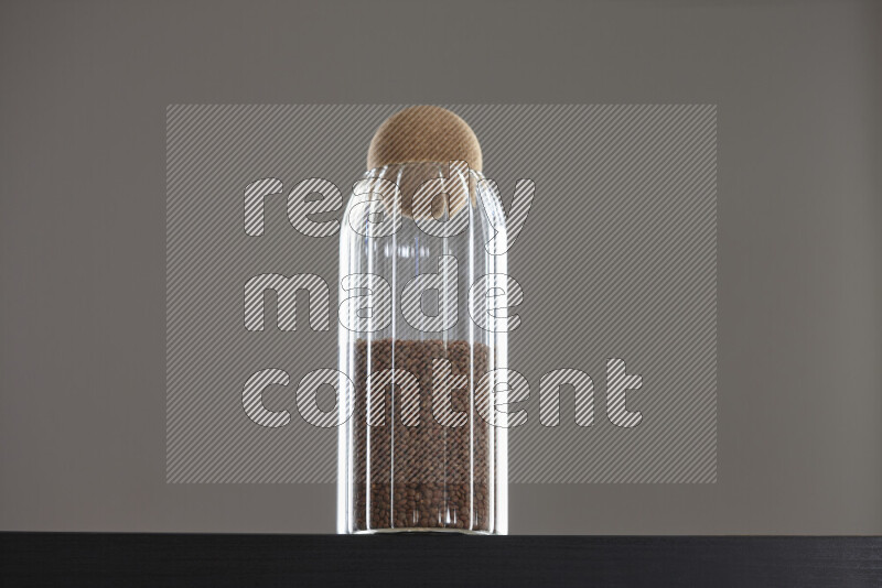 Brown lentils in a glass jar on black background