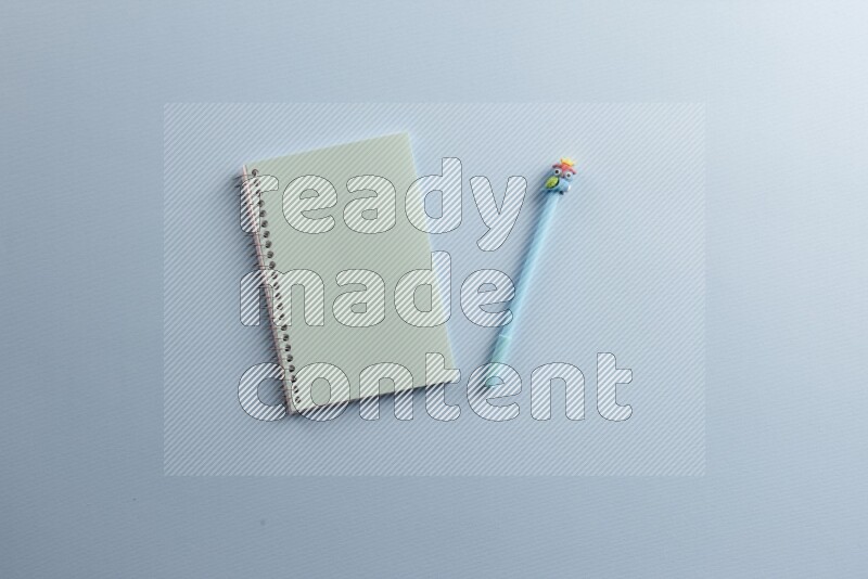 A blue notebook with different school supplies on blue background