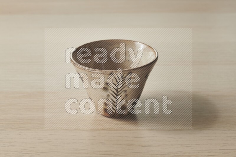 A decorative pottery bowl on light wooden background