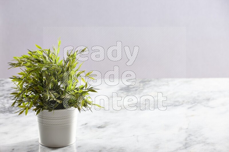 Green artificial plant in white pot on light grey marble background