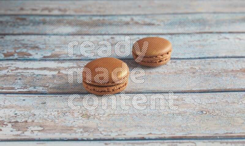 45º Shot of two Brown Coffee macarons on light blue wooden background