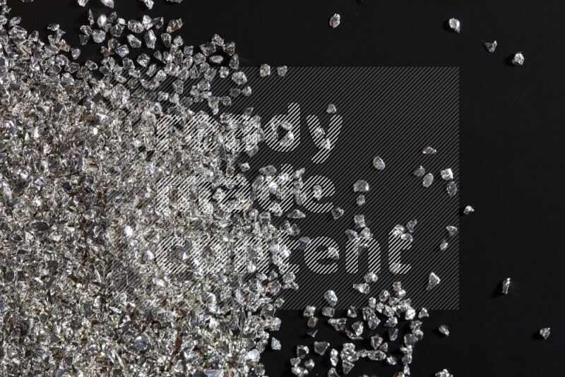 Silver shimmering fragments of glass scattered on a black background