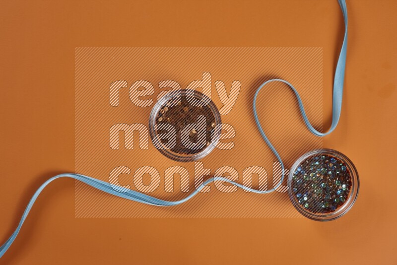 A blue collection of sewing and tailoring tools arranged on a orange background