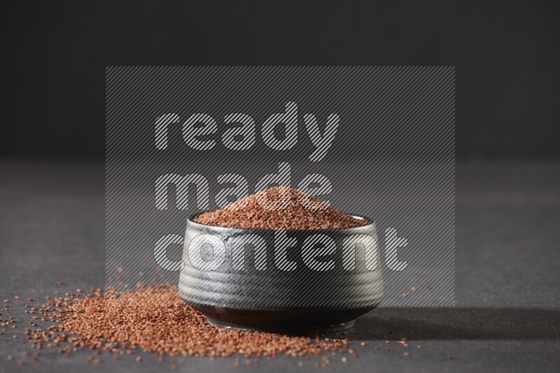 وعاء فخاري أسود ممتلئ ببذور حب الرشاد محاط بالبذور على أرضية سوداء