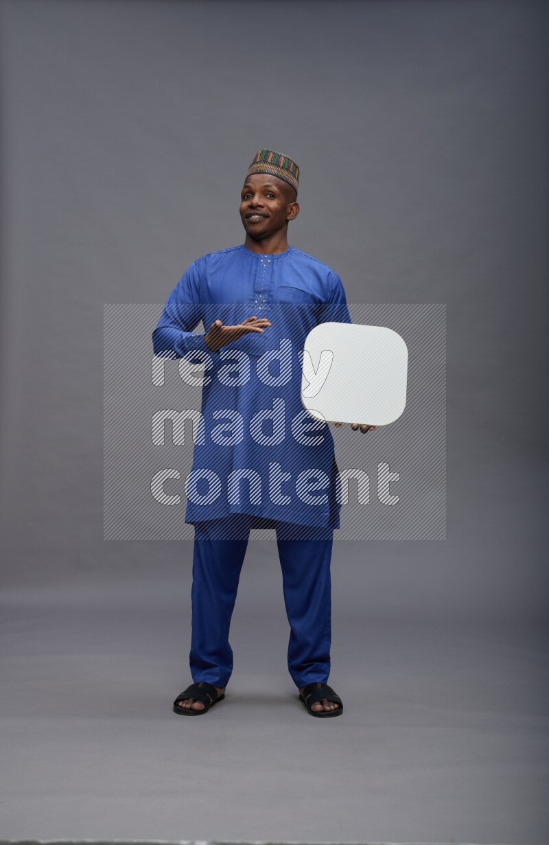 Man wearing Nigerian outfit standing holding social media sign on gray background