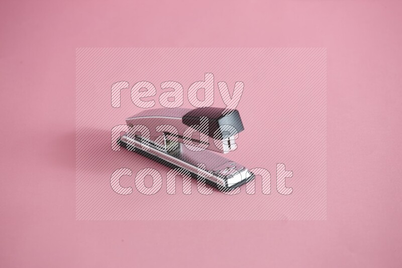 A metal stapler for paper on rose background