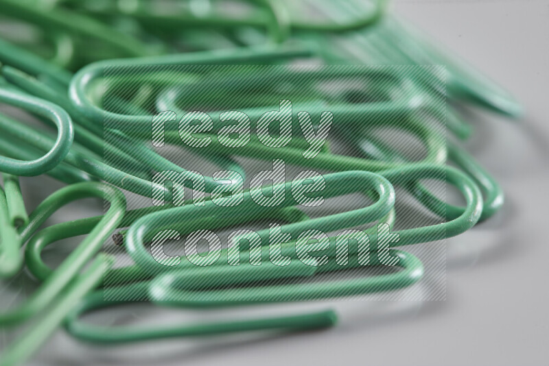 Green paper clips isolated on a grey background