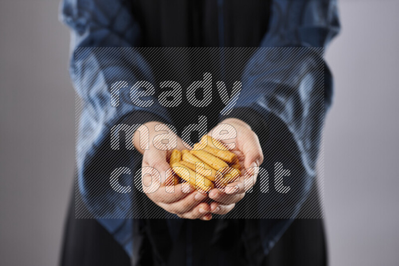 Woman in abaya holding different kinds of snacks in different positions