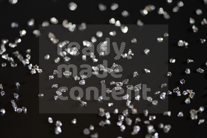 Silver shimmering fragments of glass scattered on a black background