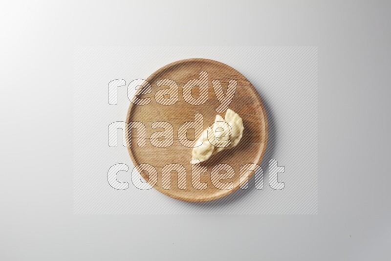 Three Sambosas on a wooden round plate on a white background