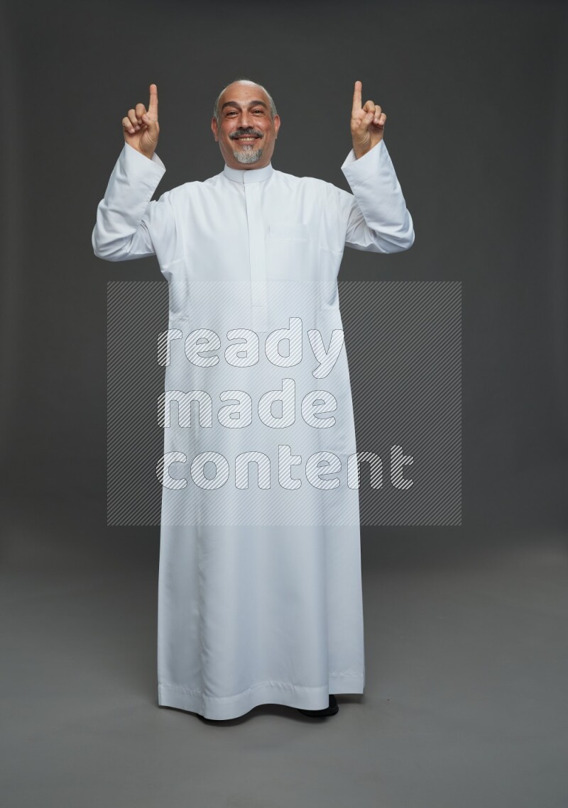 Saudi man without shomag Standing Interacting with the camera on gray background