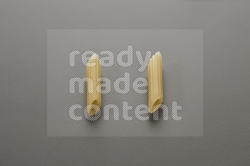 Mini penne pasta on grey background