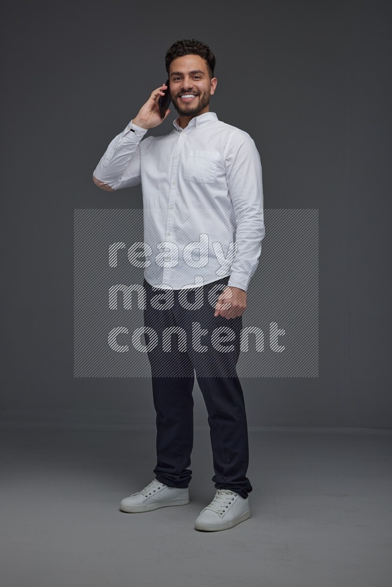 A man wearing smart casual talking in the phone eye level on a gray background