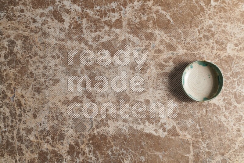 A multicolored pottery bowl on beige marble background