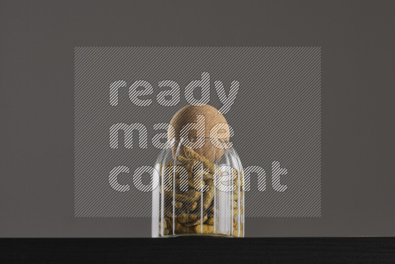 Turmeric in a glass jar on black background