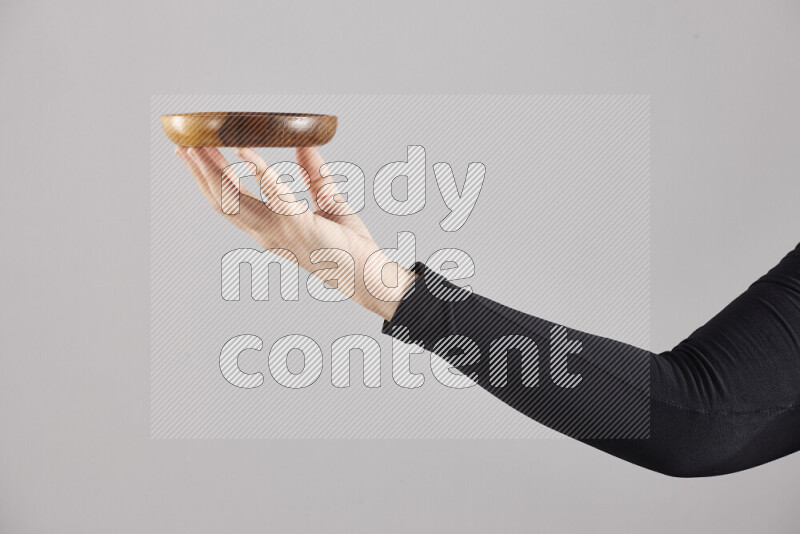 A woman in black abaya holding different wooden essentials in different positions