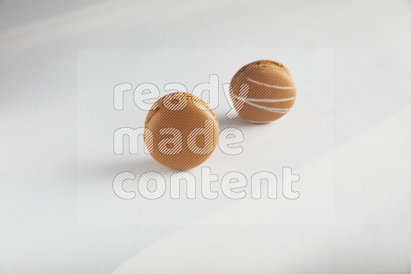 45º Shot of of two assorted Brown Irish Cream, and Brown Maple Taffy macarons  on white background