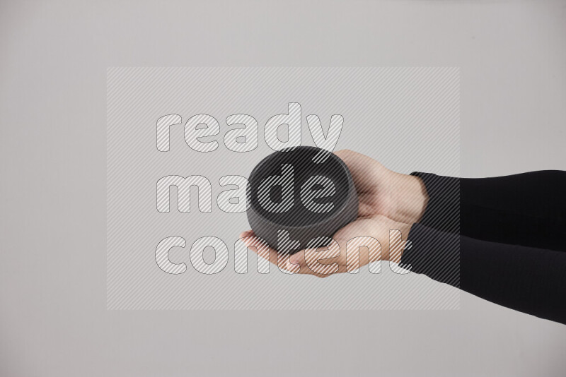 A woman in black abaya holding different pottery essentials in different positions